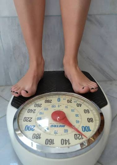 Person standing on a bathroom scale during a daily wellness check-in