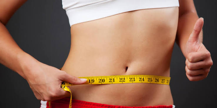 Close-up of a tape measure around a waist while tracking healthy weight-management progress